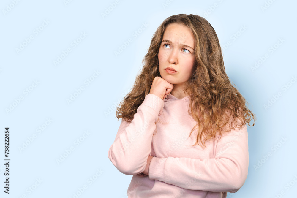 Young cute thoughtful intelligent woman with curly hair looking up, hand on chin isolated over blue background, copy space, deep thinking, creative person Young cute thoughtful intelligent woman with curly hair looking up, hand on chin isolated over blue background, copy space, deep thinking, creative person