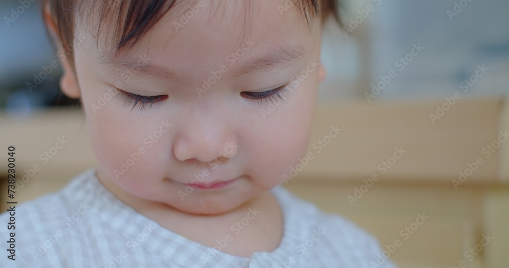 Intimate close-up of a pensive toddler with eyes cast down, in a soft-focus indoor environment. Intimate close-up of a pensive toddler with eyes cast down, in a soft-focus indoor environment.