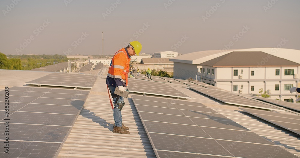 engineer worker in a high-visibility vest walks along a solar panel array on a building roof