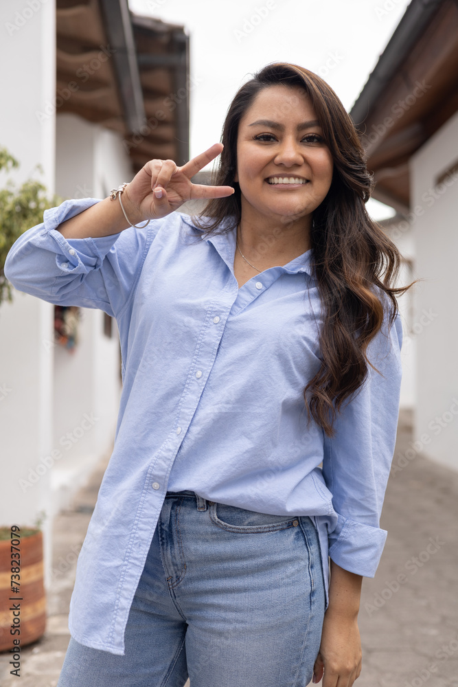 cheerful young woman posing outdoors with gesture of her fingers, beauty of young attractive woman wearing casual clothes, youth fashion in city, fun