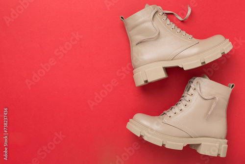 Beige trendy boots on color background, top view.