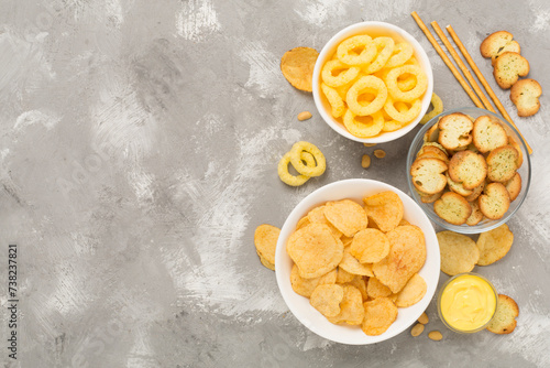 Various unhealthy snacks on concrete background, top view