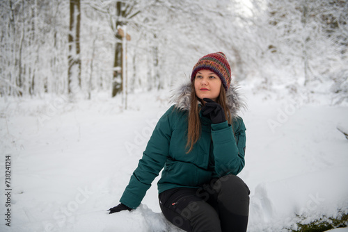 Contemplative Woman Seated in a Snowy Forest Setting