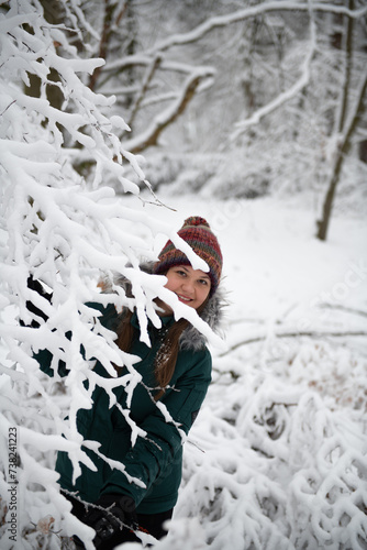 Smiling Woman Peeking Through Snow-Covered Branches
