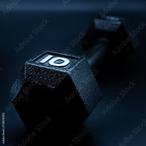 Black ten pound dumbbell weight on a dark background 