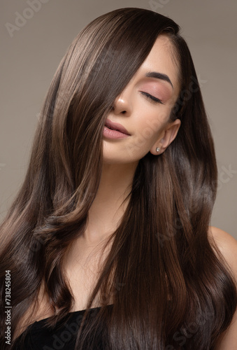 Portrait of a brunette girl with gorgeous long hair. Gray background.