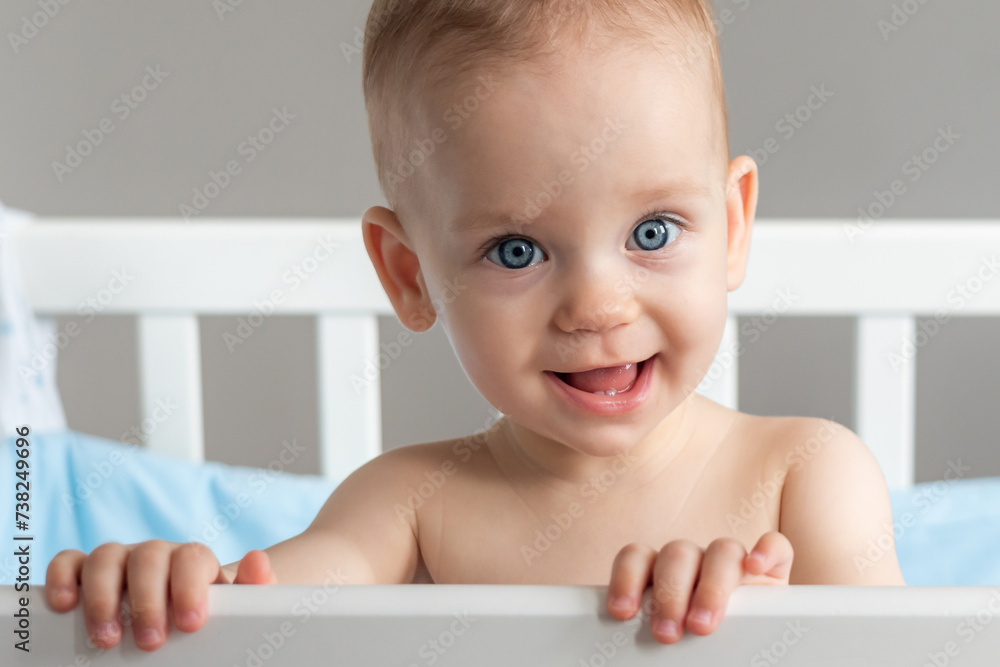 One year old baby standing in a crib smiling One year old baby standing in a crib smiling