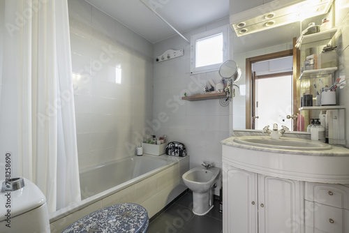 A bathroom furnished a few years ago with white cabinet with sink  mirror and integrated lights