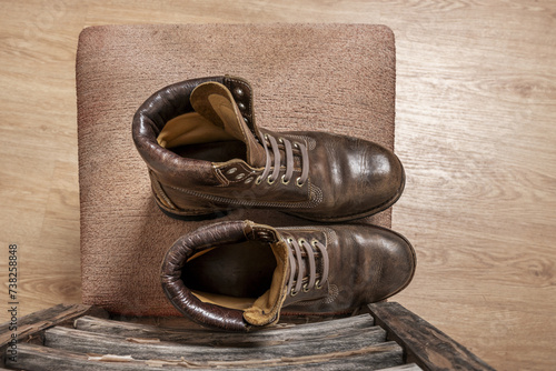 A brown leather hiking boot with triple stitching on an old seat viewed from the top