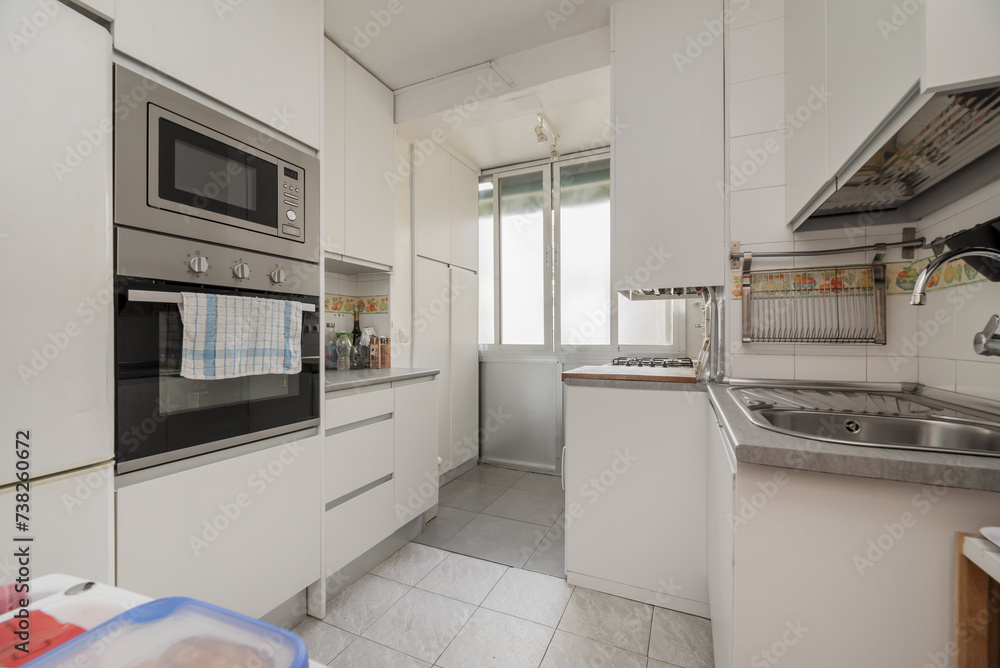 Image of a small kitchen with all the walls covered in white furniture and integrated appliances Image of a small kitchen with all the walls covered in white furniture and integrated appliances