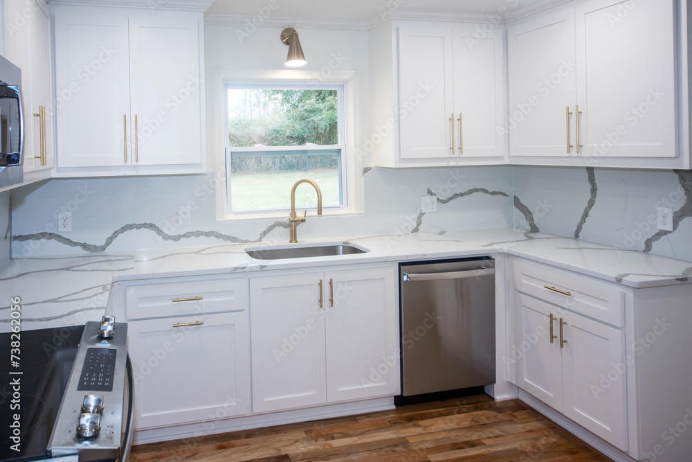 A light and bright newly remodeled white kitchen with quartz countertops, white shaker cabinets and gold hardware and stainless appliances - obrazy, fototapety, plakaty 