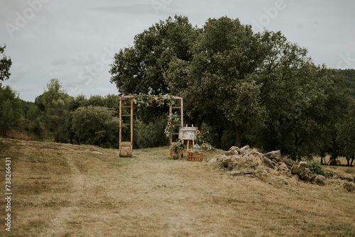 General entrance shot to the forest, it has been decorated with the frame of an old wooden door and floral decorations. The olive branches, sunflowers and eucalyptus stand out. Vintage style, wooden b