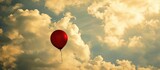 Solitary red balloon drifting amidst cloudy skies.