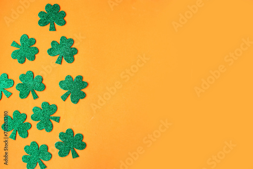 Happy St. Patricks Day. Shamrocks pattern on bright orange background. Copy space for the text