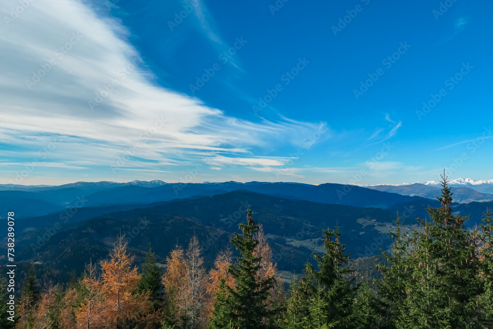 Idyllic hiking trail along alpine pasture with panoramic view of mountain ranges of Lower and Higher Tauern seen from Grebenzen, Gurktal Alps, Styria, Austria. Calm serene atmosphere in Austrian Alps