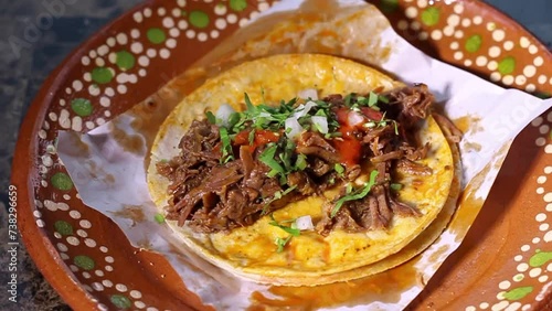 Slow motion of person putting cilantro and onion in beef birria taco. Mexican food photo