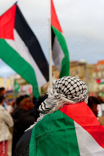 A person wearing Palestinian keffiyeh. Pro-Palestinian protests. Anti-Israel protesters. Palestine Flags. Free Palestine.