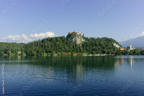 castle close up look on top of hill surrounded by green nature and lake below with clear blue waters photo