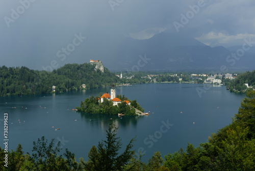 tiny island with church tower and nature in the middle of gorgeous clear water blue lake photo