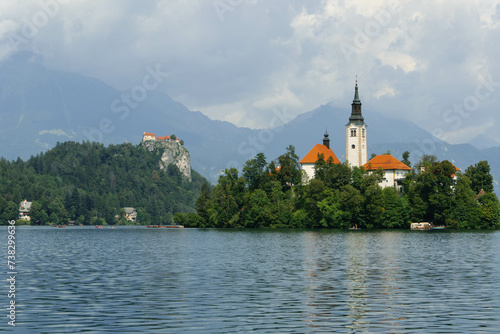 tiny island with church tower and nature in the middle of gorgeous clear water blue lake photo