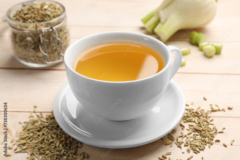 Fennel tea in cup, seeds and fresh vegetable on light wooden table, closeup Fennel tea in cup, seeds and fresh vegetable on light wooden table, closeup