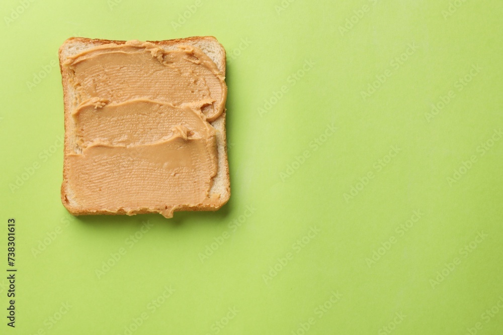 Tasty peanut butter sandwich on light green background, top view. Space for text