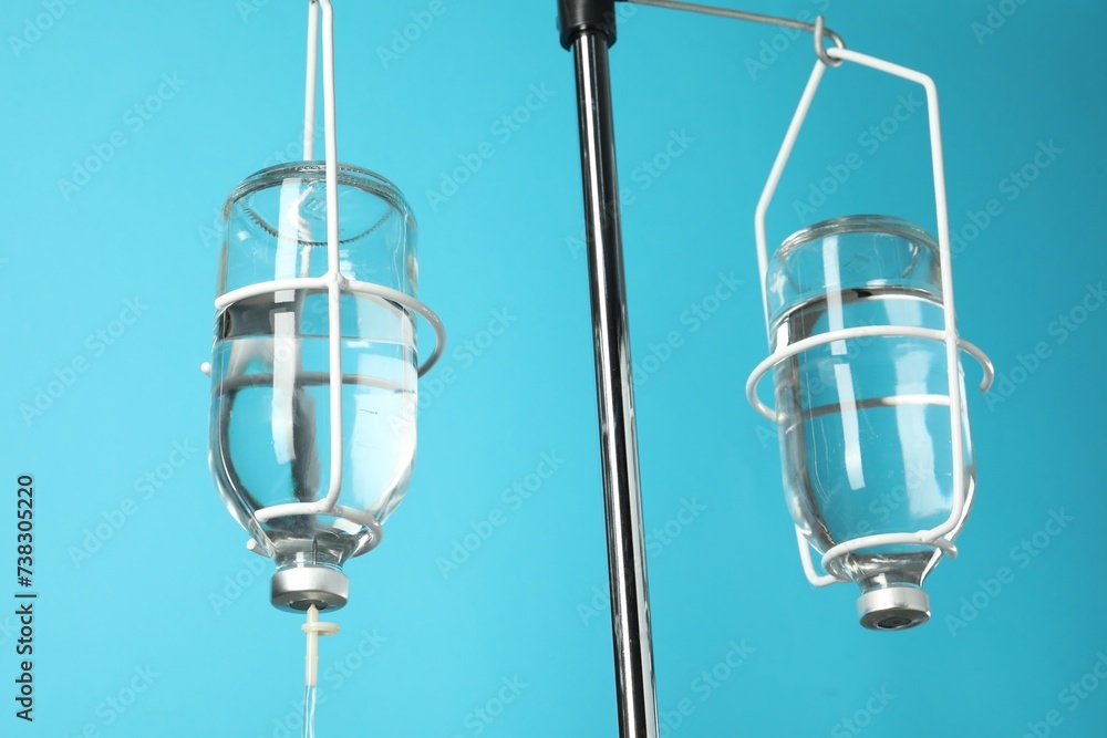 IV infusion set on pole against light blue background, closeup IV infusion set on pole against light blue background, closeup