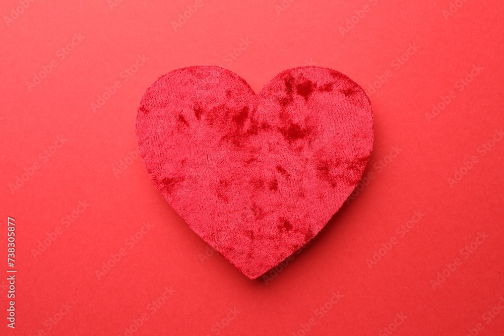 One velvet heart on red background, top view One velvet heart on red background, top view