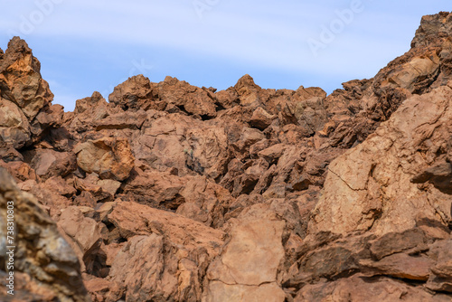 Hiking around Piedras Amarillas rock formation in El Teide crater on Tenerife. Orange volcanic cliffs.