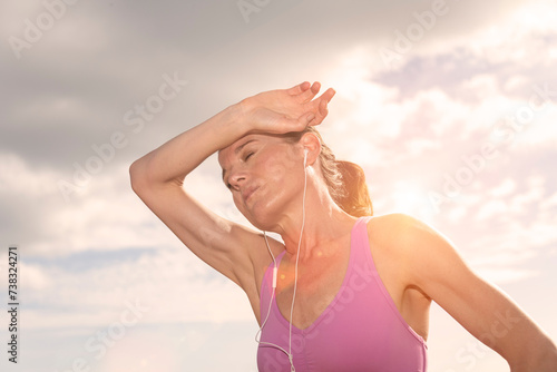 sporty woman hot after exercise in the sun,  hand to head