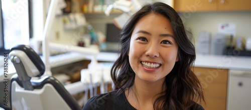 Asian woman sitting at the dentist, smiling for a portrait.