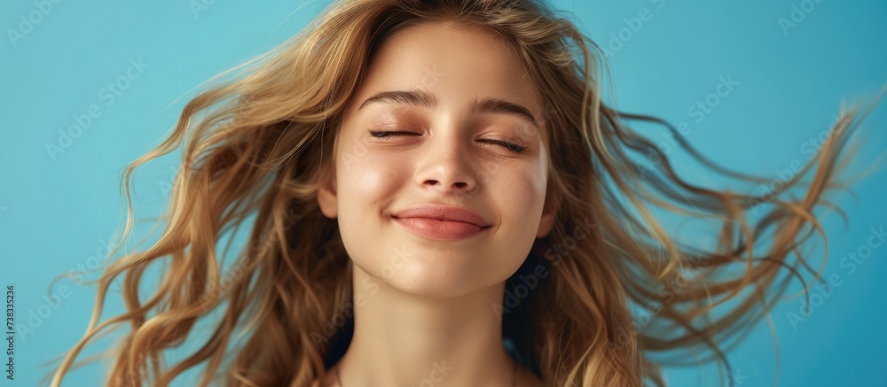 Close-up portrait of a healthy, cheerful girl with wavy hair isolated on a bright blue background. Close-up portrait of a healthy, cheerful girl with wavy hair isolated on a bright blue background.