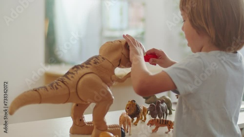 Child playing with dinosaur and animal toys on a table. Educational and developmental activities concept for design and print. photo