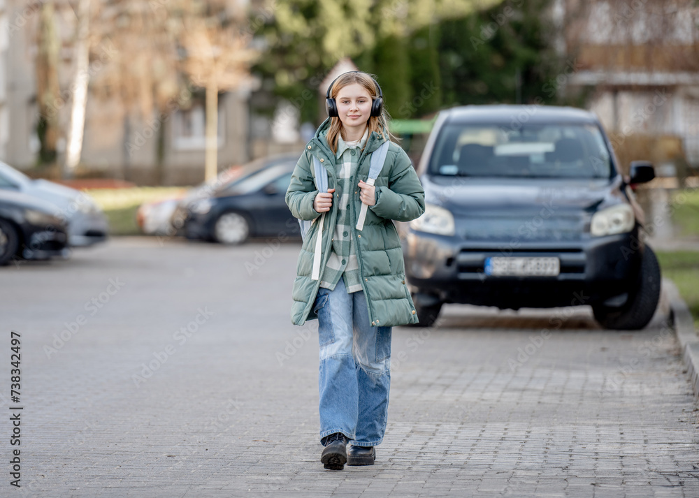 Sweet Girl Walks Down Street In Early Spring, Listening To Music In Headphones