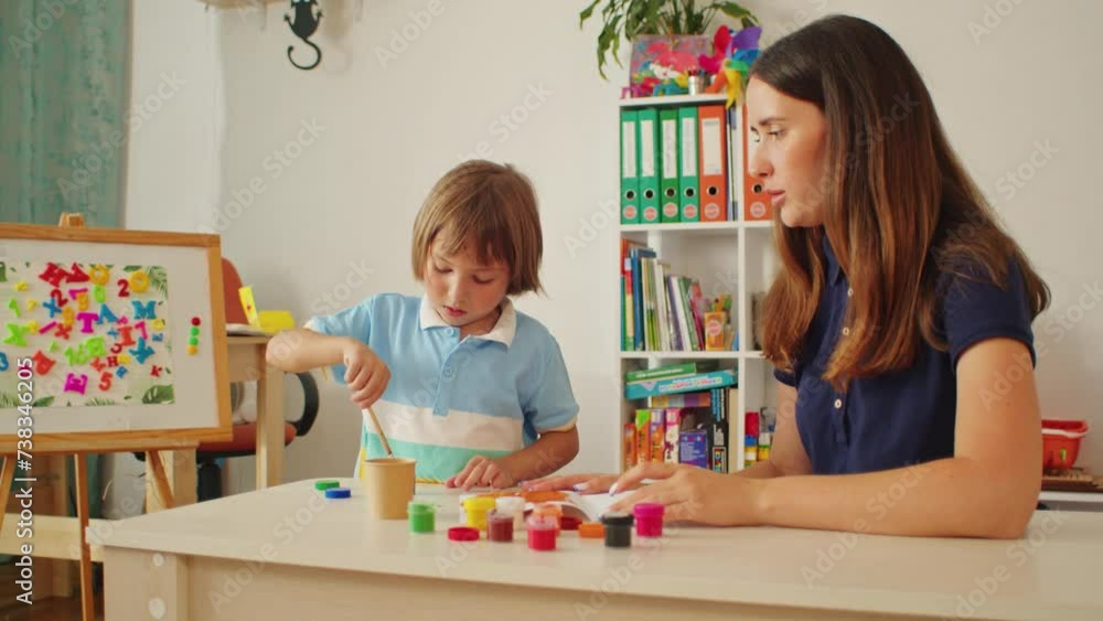 Child with adult painting with colorful paints at a table. Creative ...