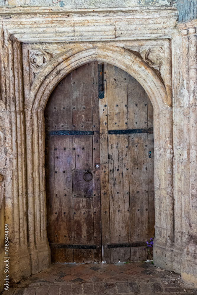 Closed medieval wooden arched door with a beautifully decorated stone frame