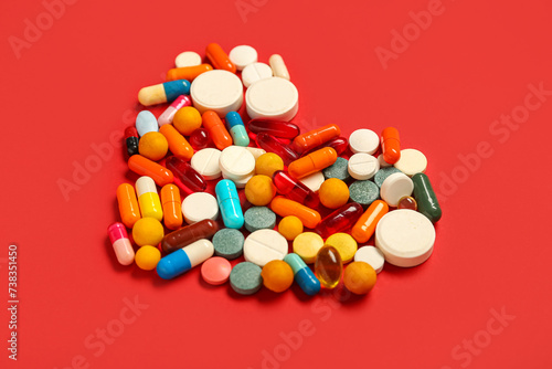 Heart made of different pills on red background