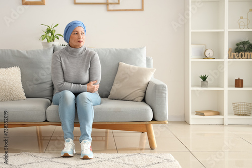 Mature woman after chemotherapy sitting on sofa at home. Stomach cancer concept © Pixel-Shot