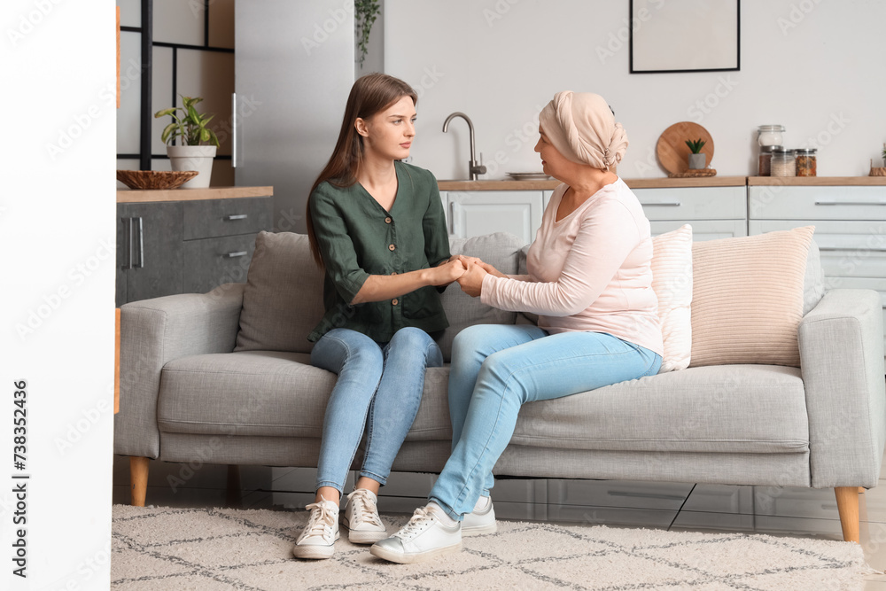 Mature woman after chemotherapy with her daughter holding hands at home. Stomach cancer concept Mature woman after chemotherapy with her daughter holding hands at home. Stomach cancer concept