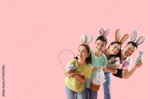 Happy family in bunny ears with Easter gifts on pink background