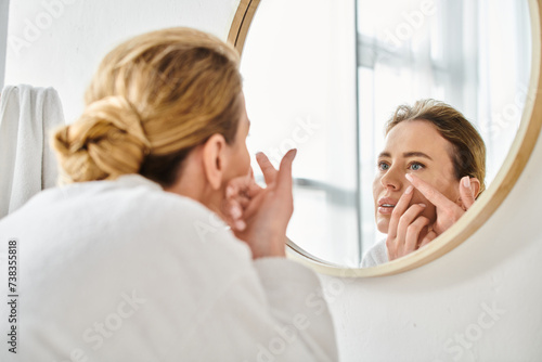 attractive woman in white comfy bathrobe wearing her contact lenses near mirror in bathroom