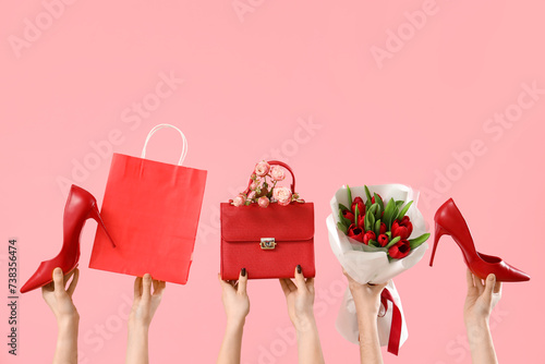 Female hands with bouquet of tulips, high heel shoes and handbag on pink background. Shopping for International Women's Day