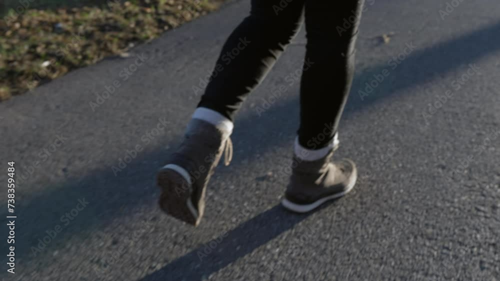 Close-up person wearing boots walking on asphalt sidewalk, pedestrian going forward during sunset Close-up person wearing boots walking on asphalt sidewalk, pedestrian going forward during sunset