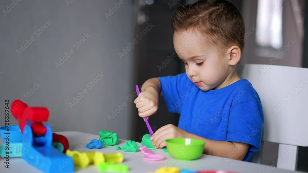 Interested baby boy is cutting the plasticine with a stick. Sculpturing as a hobby for kid. Interested baby boy is cutting the plasticine with a stick. Sculpturing as a hobby for kid.