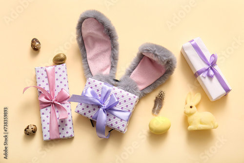 Bunny ears with Easter eggs and gift boxes on beige background