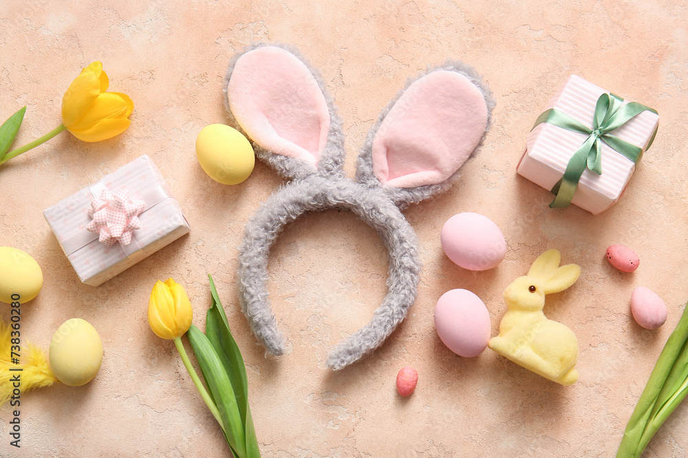 Bunny ears with Easter eggs, tulip flowers and gift boxes on beige grunge background Bunny ears with Easter eggs, tulip flowers and gift boxes on beige grunge background