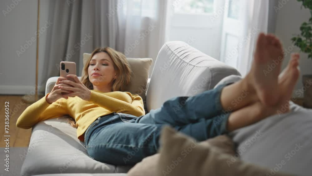 Laying model watching mobile phone screen at comfortable sofa. Chilling woman Laying model watching mobile phone screen at comfortable sofa. Chilling woman