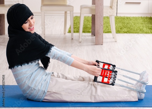 Young woman in hijab doing exercises at home