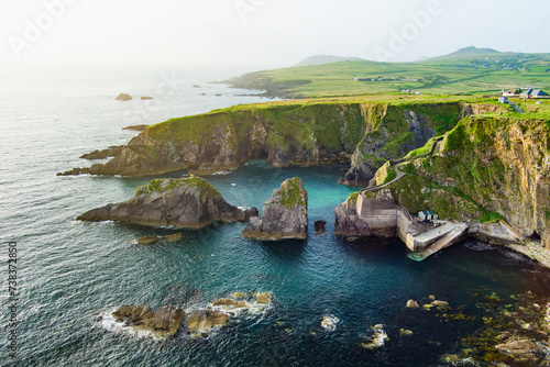 Dunquin or Dun Chaoin pier, Ireland's Sheep Highway. Aerial view of narrow pathway winding down to the pier, ocean coastline, cliffs. Popular location on Slea Head Drive and Wild Atlantic Way. photo