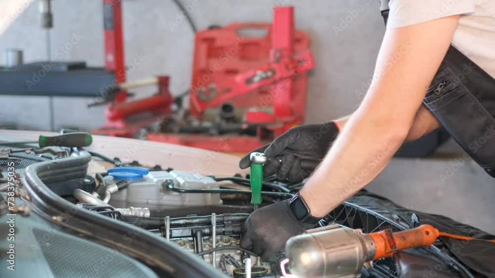 Mechanic repairing automotive tire in garage using wood and auto parts Mechanic repairing automotive tire in garage using wood and auto parts